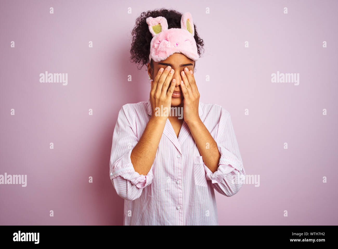Young african american woman wearing pajama and mask over isolated pink background rubbing eyes for fatigue and headache, sleepy and tired expression. Stock Photo
