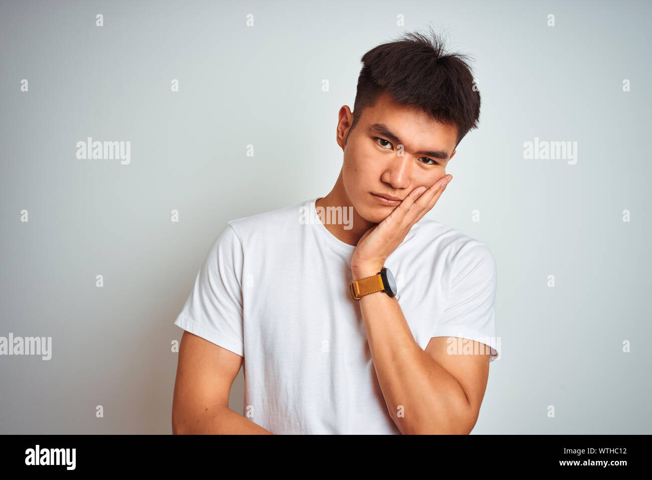 Young asian chinese man wearing t-shirt standing over isolated white ...