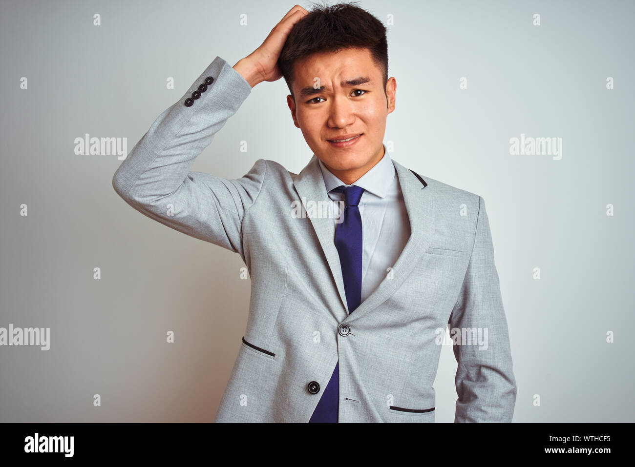 Asian chinese businessman wearing grey jacket and tie standing over isolated white background confuse and wonder about question. Uncertain with doubt, Stock Photo