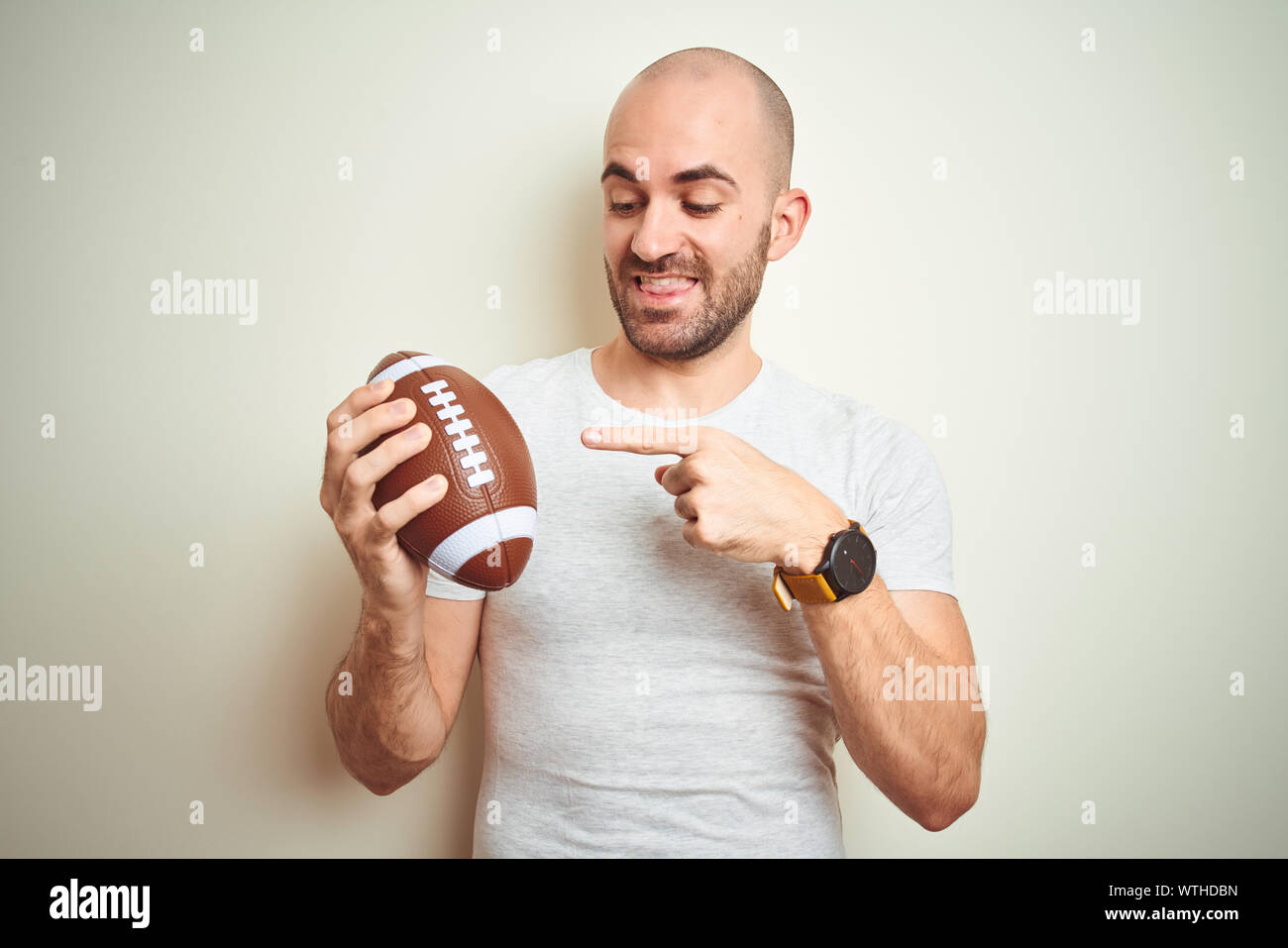 Young man holding rugby american football ball over isolated background very happy pointing with hand and finger Stock Photo