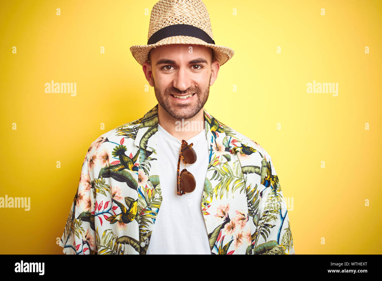 Young man on vacation wearing hawaiian flowers shirt and summer hat ...