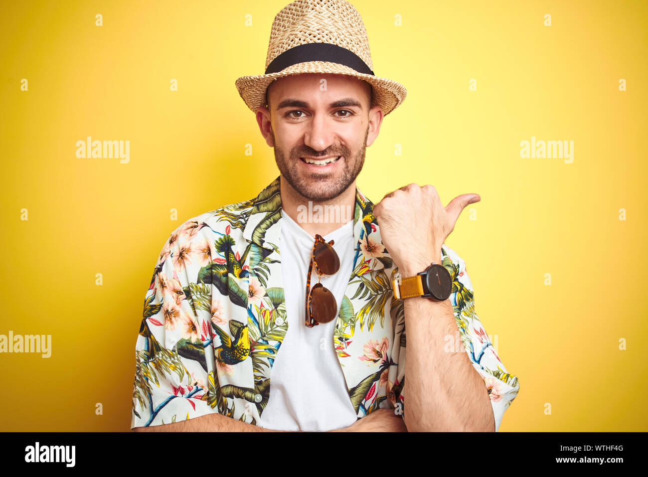 Young man on vacation wearing hawaiian flowers shirt and summer hat ...