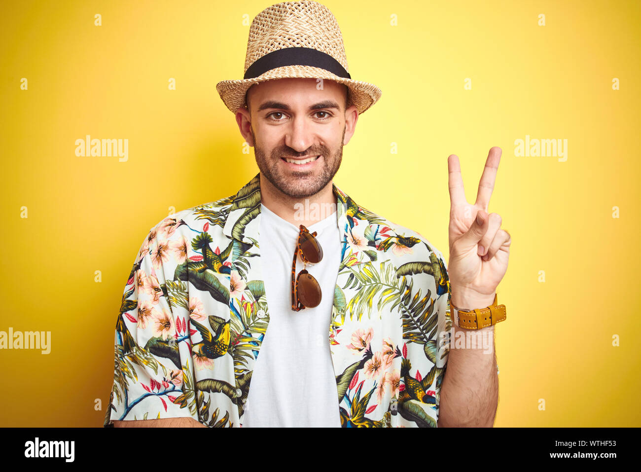 Young man on vacation wearing hawaiian flowers shirt and summer hat ...