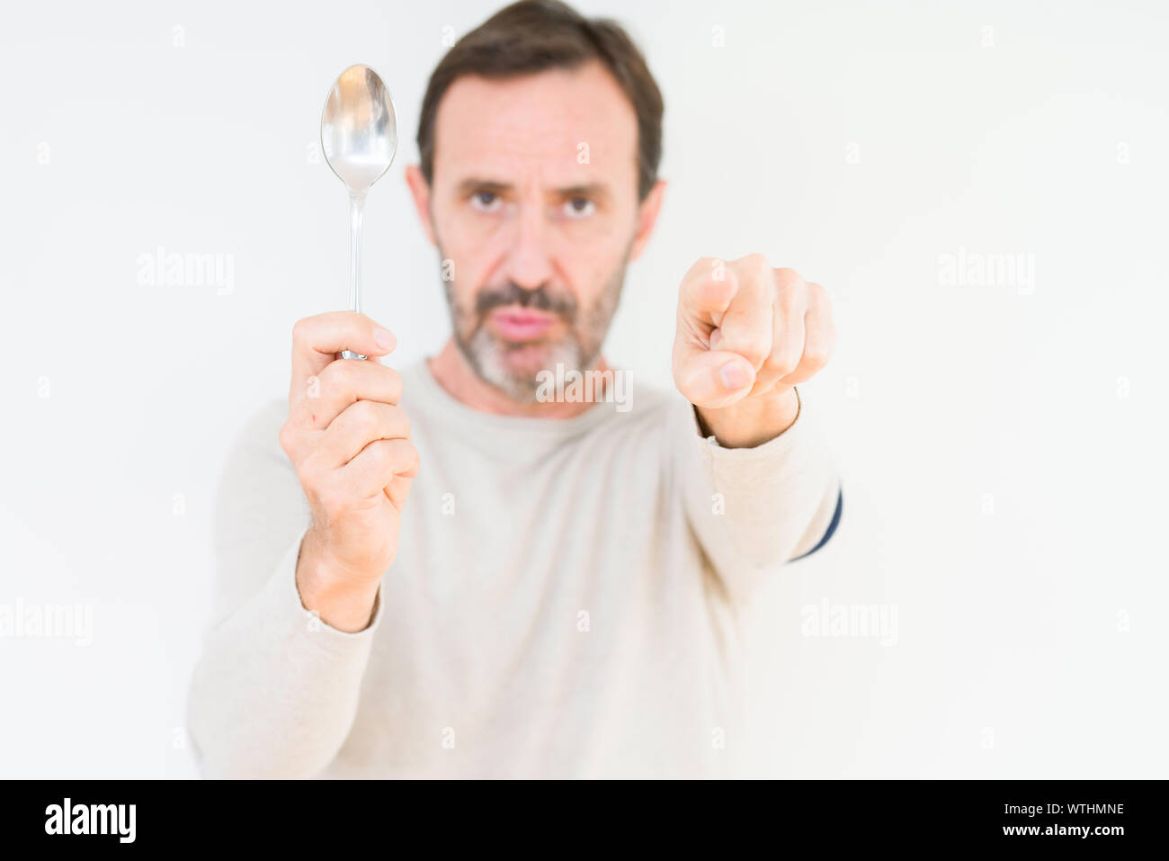 Senior man holding silver spoon over isolated background pointing with  finger to the camera and to you, hand sign, positive and confident gesture  from Stock Photo - Alamy