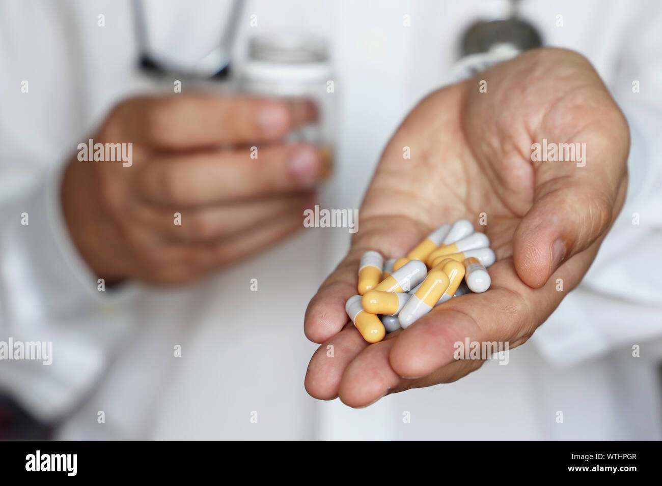 Doctor giving pills, physician holding in palm of hand medication in capsules. Concept of dose of drugs during cold season, vitamins, medical exam Stock Photo