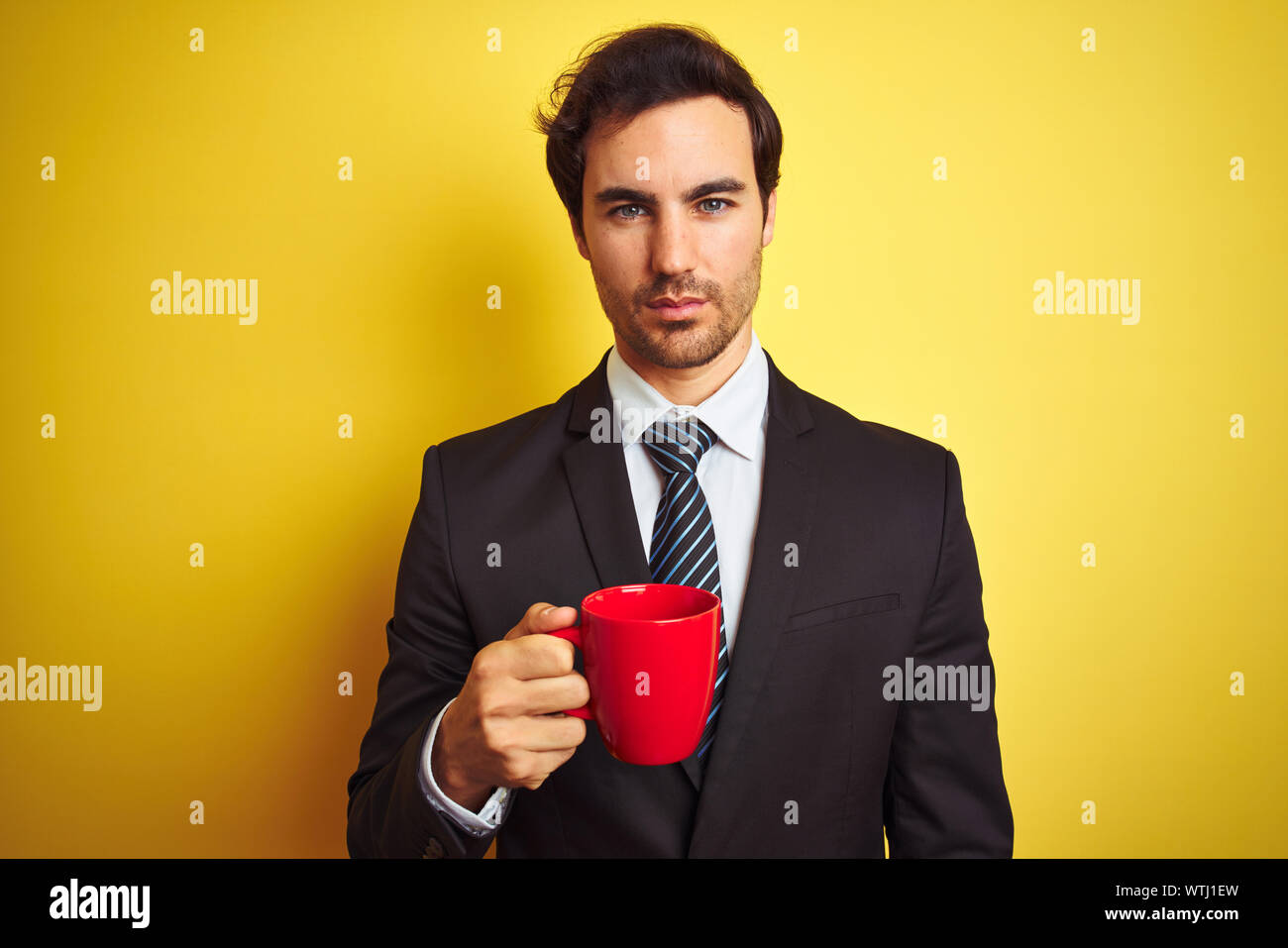 Young handsome businessman drinking red cup of coffee over isolated ...