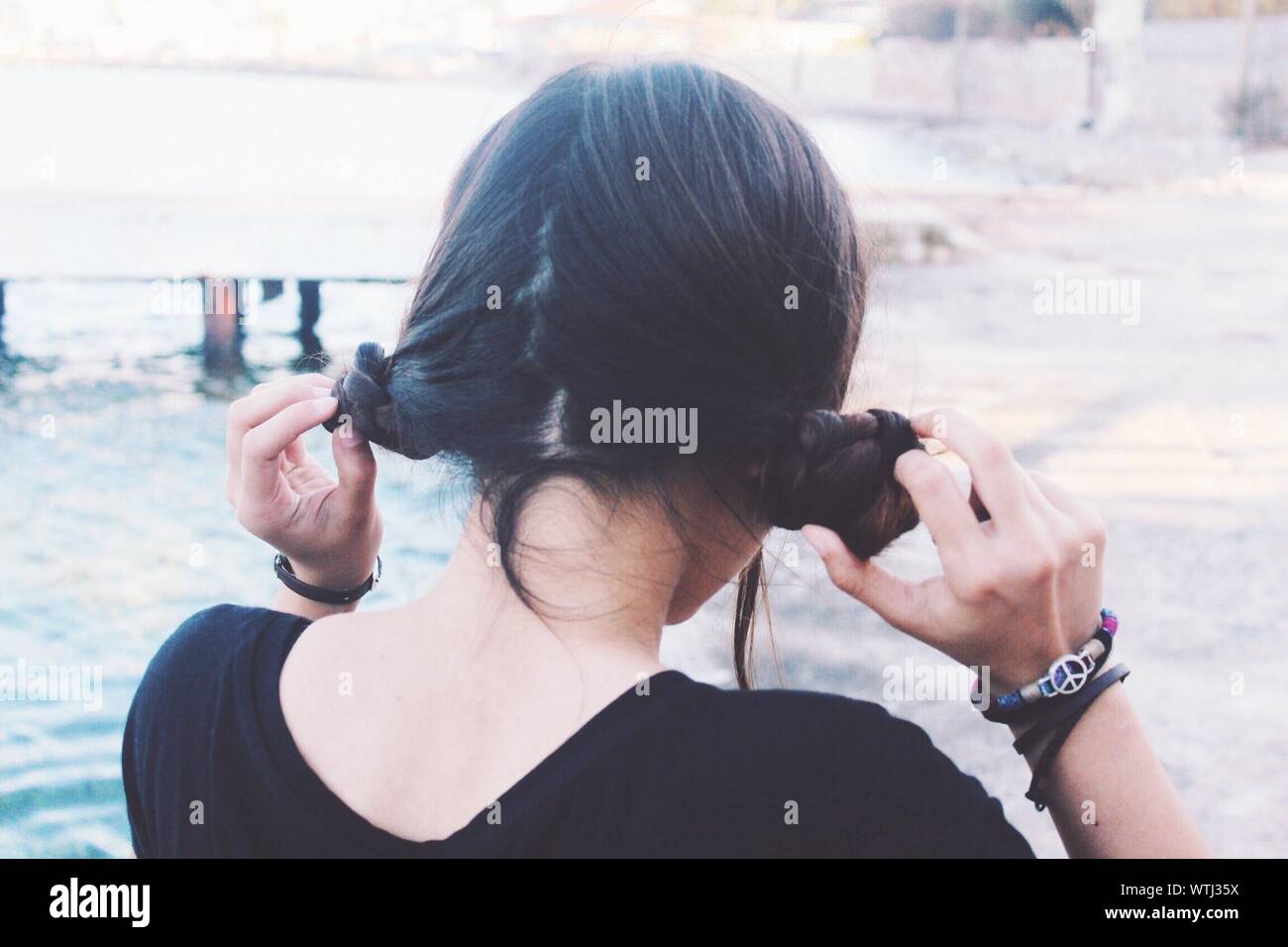 Rear View Of Woman Holding Pigtails Stock Photo