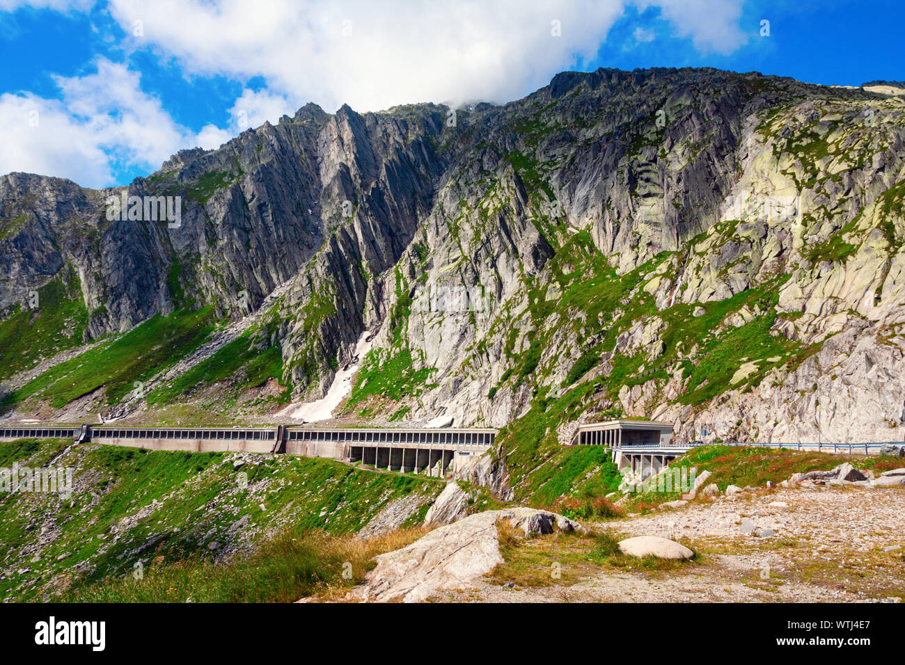 Gotthard Pass with National Road 2 running along steep cliffs of the Alps, protected with a concrete cover against falling rocks. Tessin, Switzerland. Stock Photo