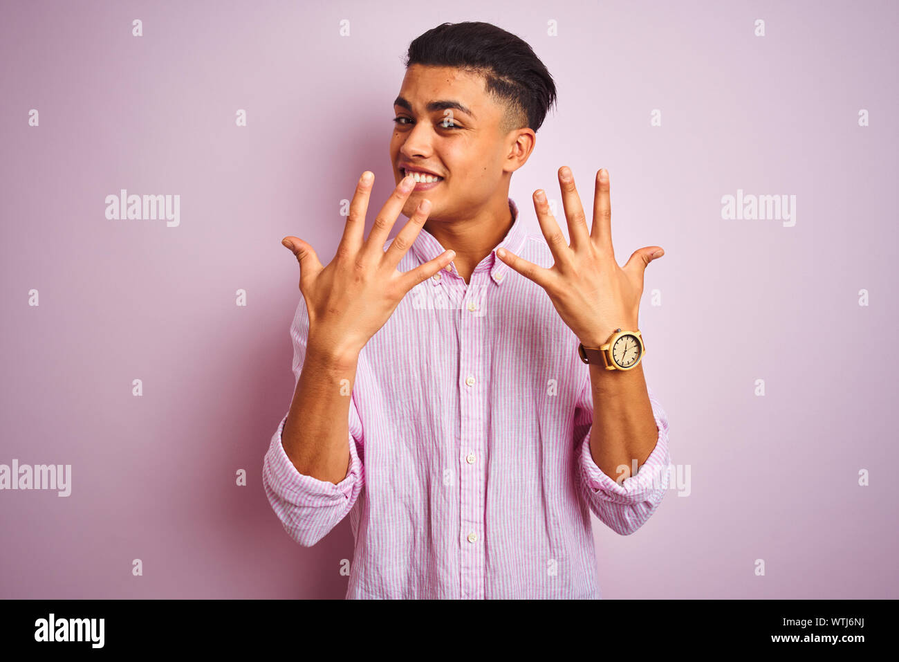 Young brazilian man wearing shirt standing over isolated pink ...