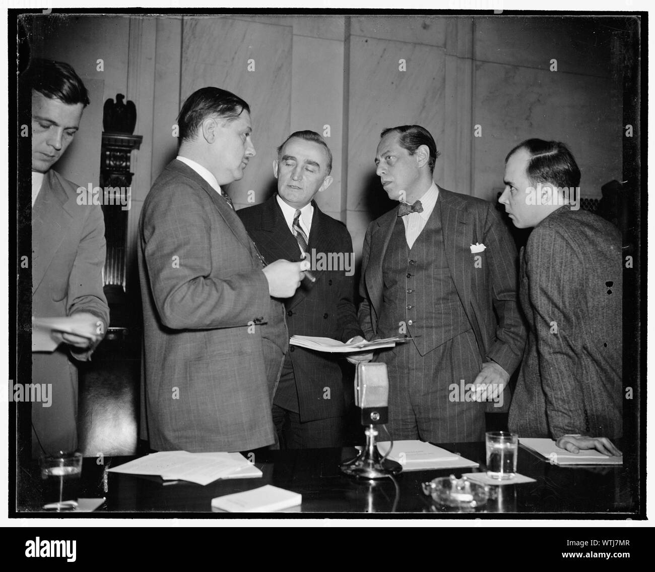 Monopoly huddle. Washington, D.C., Dec. 12. At this informal conference just before the Monopoly Committee opened today's hearing can be seen, left to right: Assistant Attorney General Thurman Arnold, Chairman Joseph C. O'Mahoney, S.E.C. Commissioner Jerome Frank, and Hugh B. Cox, Special Assistant to the Attorney General. In opening today's hearing on the glass industry's patent policies, Cox said the Justice Department seeks to disclose the relation between patent laws and enforcement of anti-trust laws, 12/12/38 Stock Photo