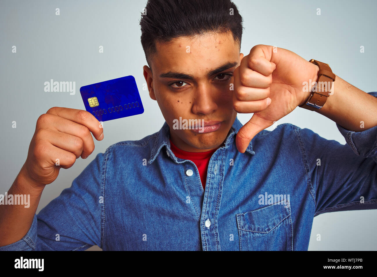 Young brazilian customer man holding credit card standing over isolated ...