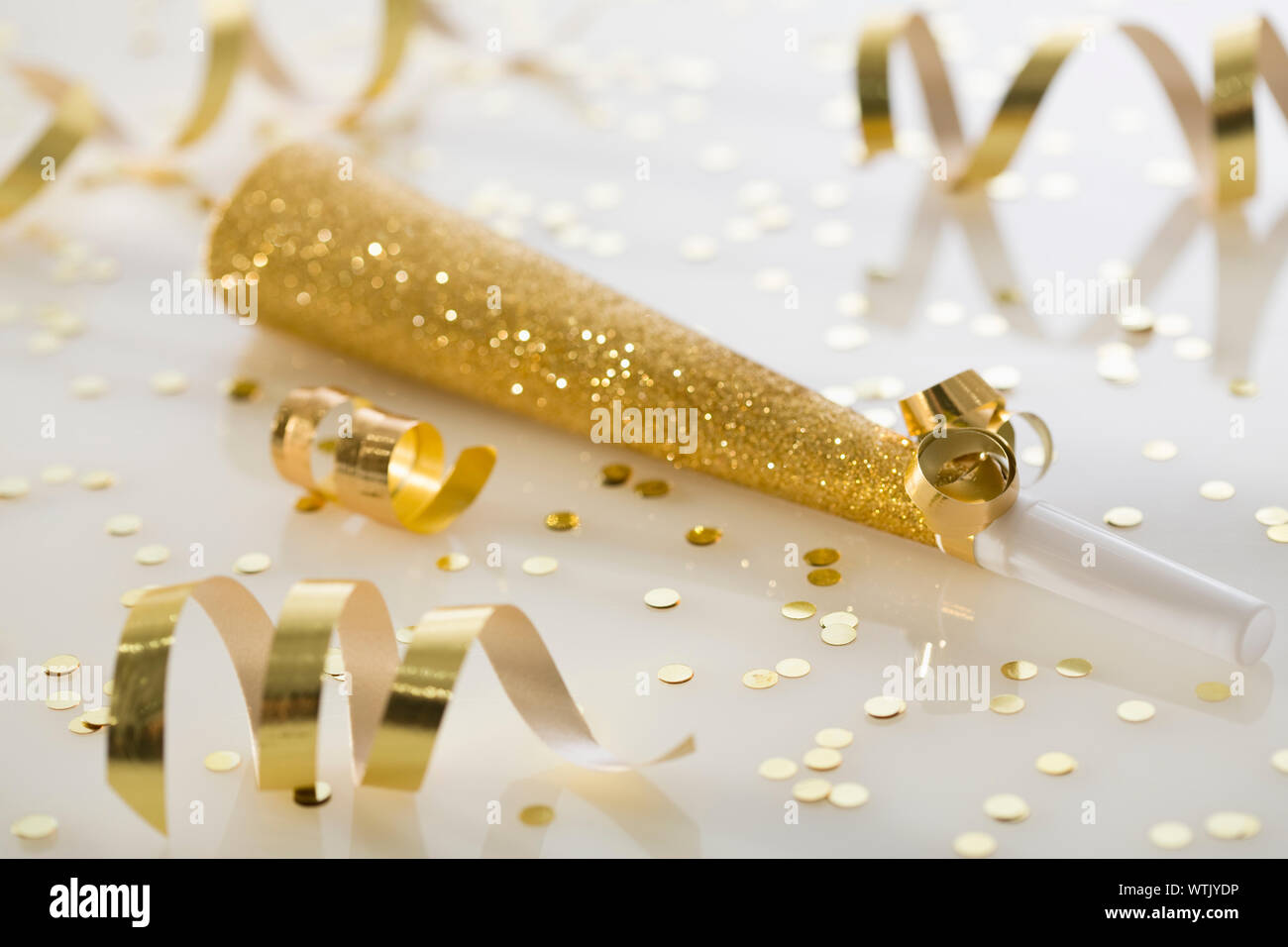 Studio shot of gold party horn and confetti Stock Photo Alamy