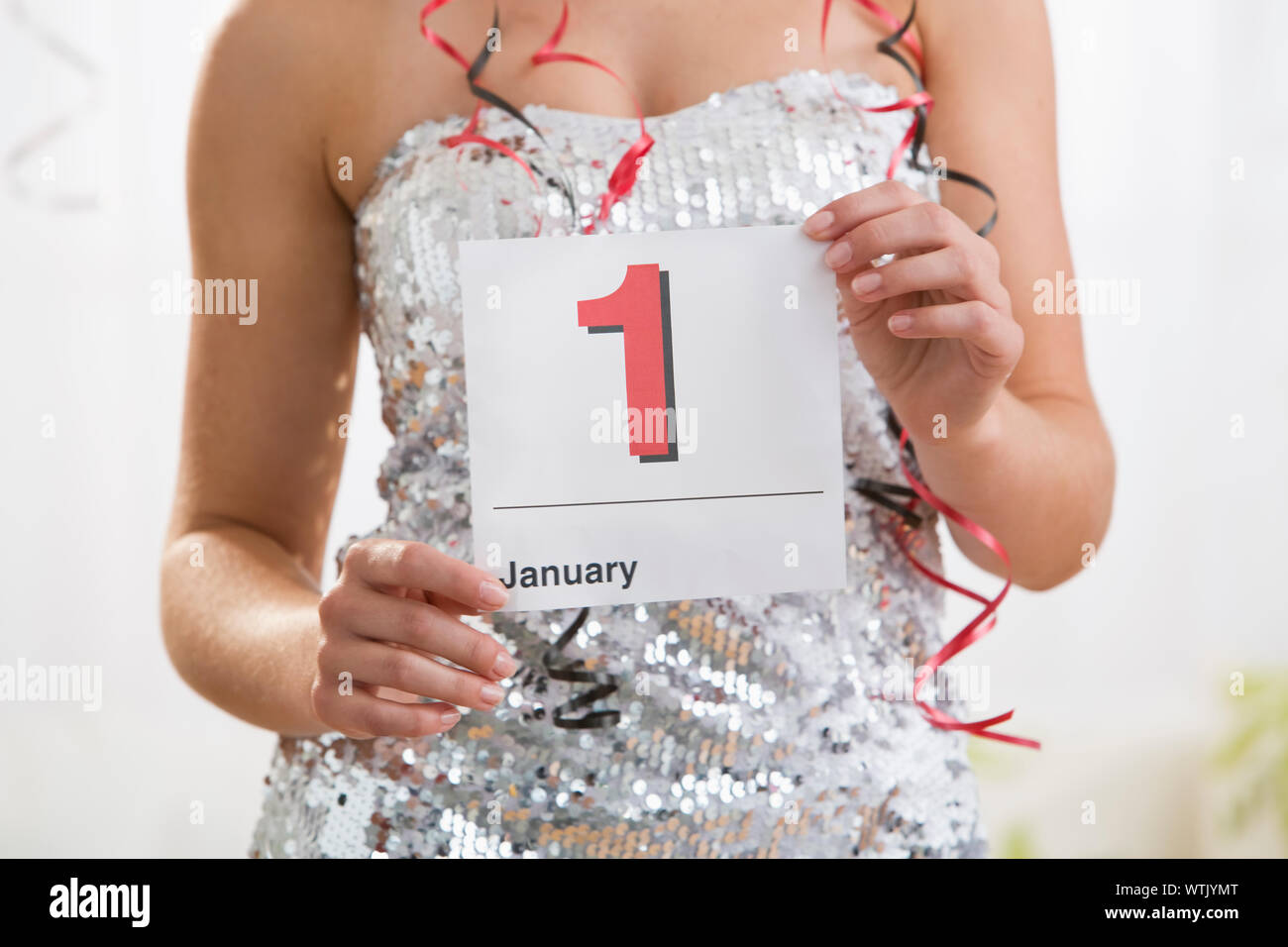 Teenage girl (16-17) in sequin dress holding calendar showing New Year's Day Stock Photo
