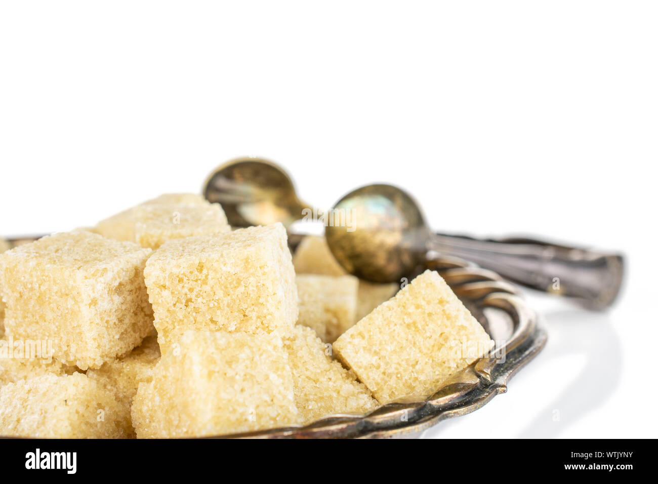 Lot of whole sweet brown sugar cube in metal bowl with sugar tongs