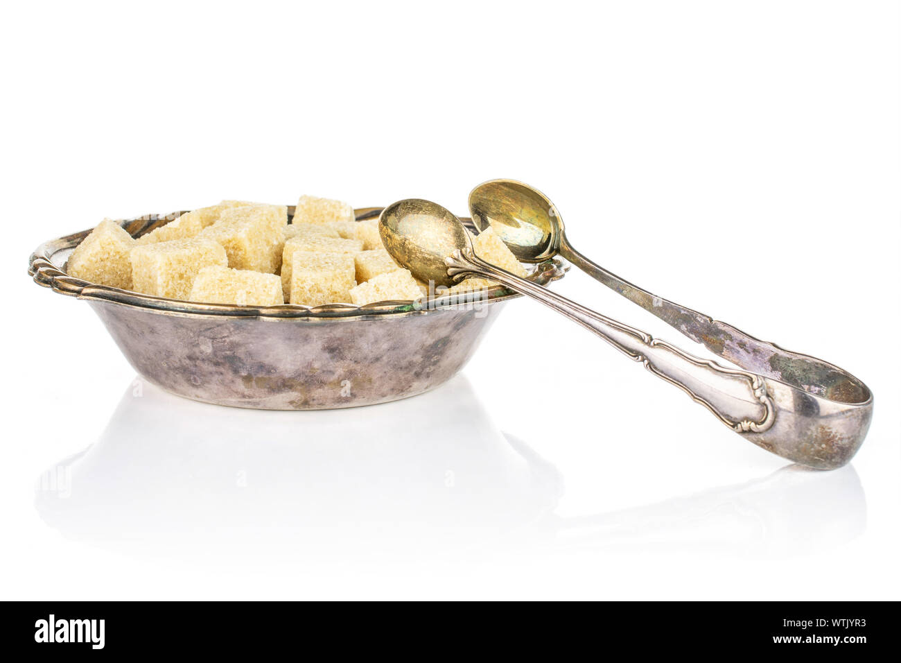 Lot of whole sweet brown sugar cube in metal bowl with sugar tongs