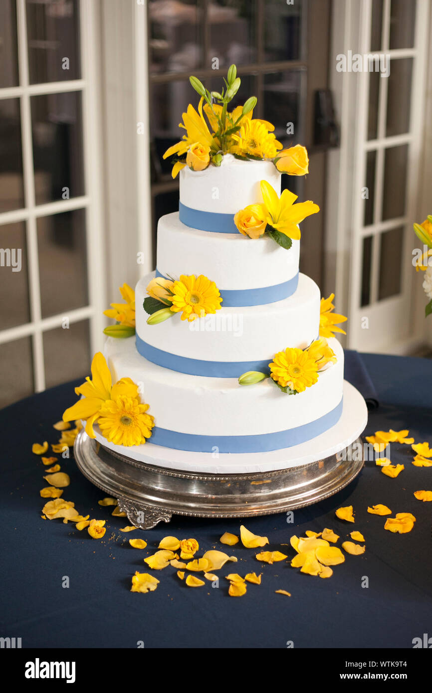 four tiered wedding cake with blue stripes and yellow flowers Stock Photo