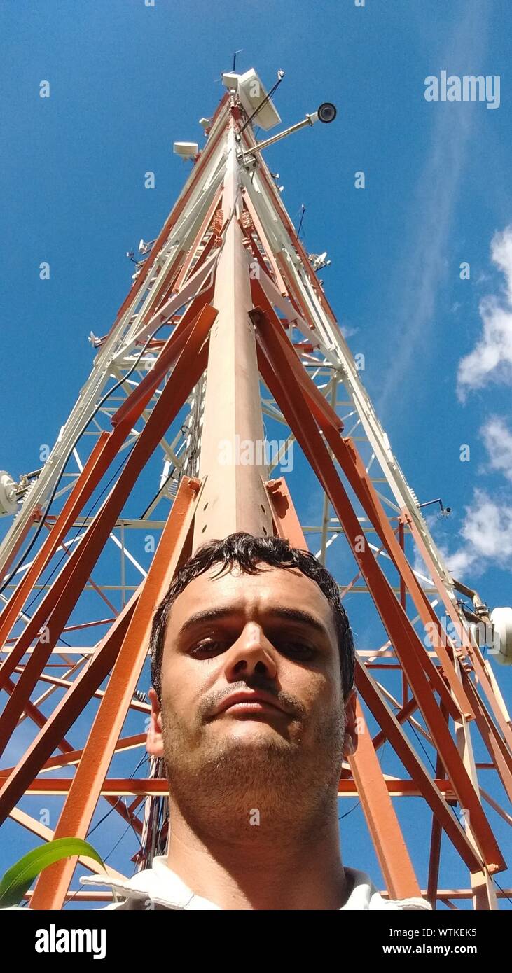 Portrait Of Young Man Against Tall Tower Stock Photo
