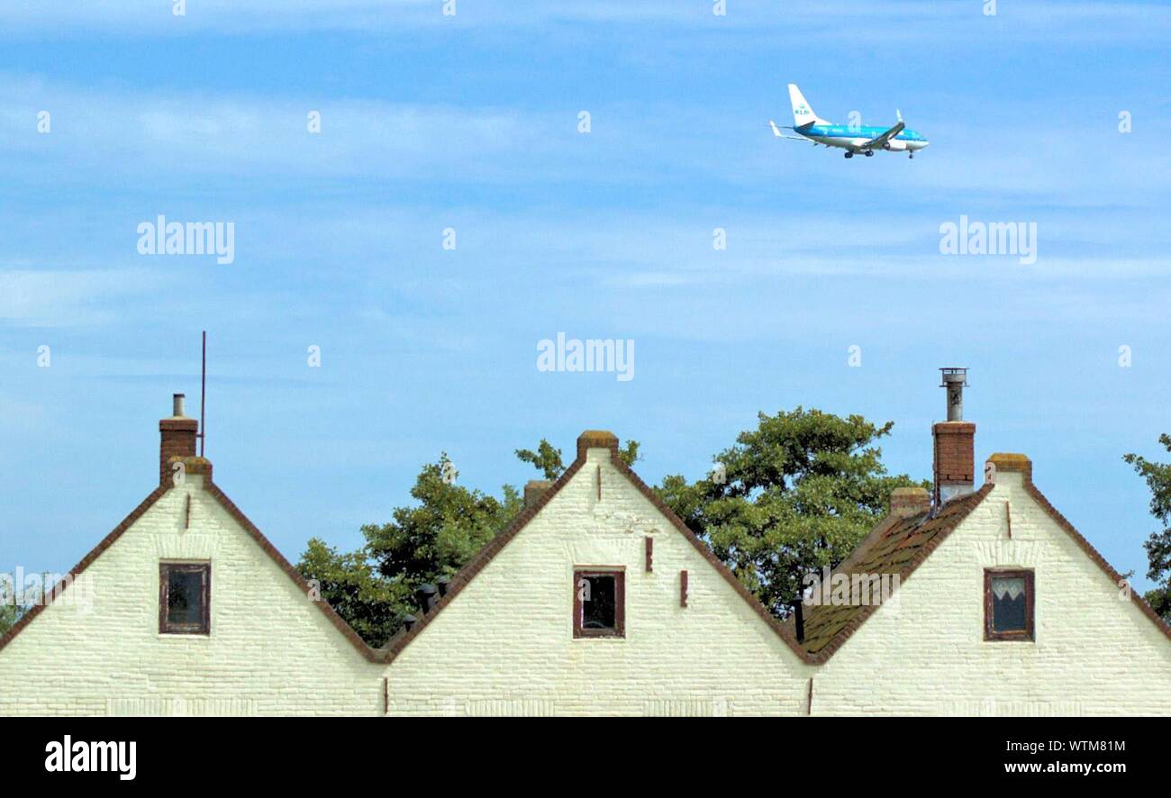 Airplane Above Houses Stock Photo