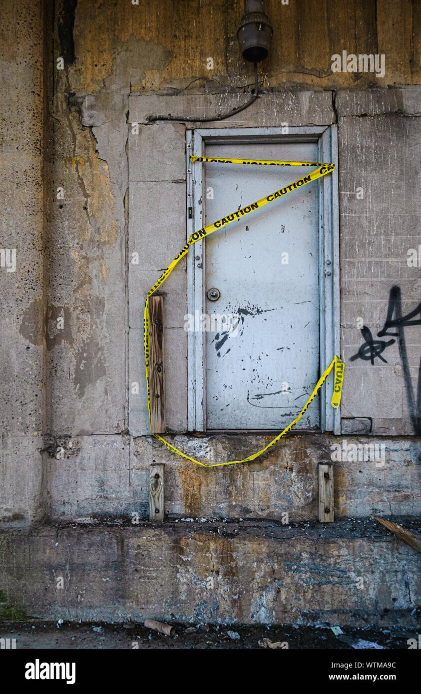 A door with yellow caution tape on it on an old abandoned cement