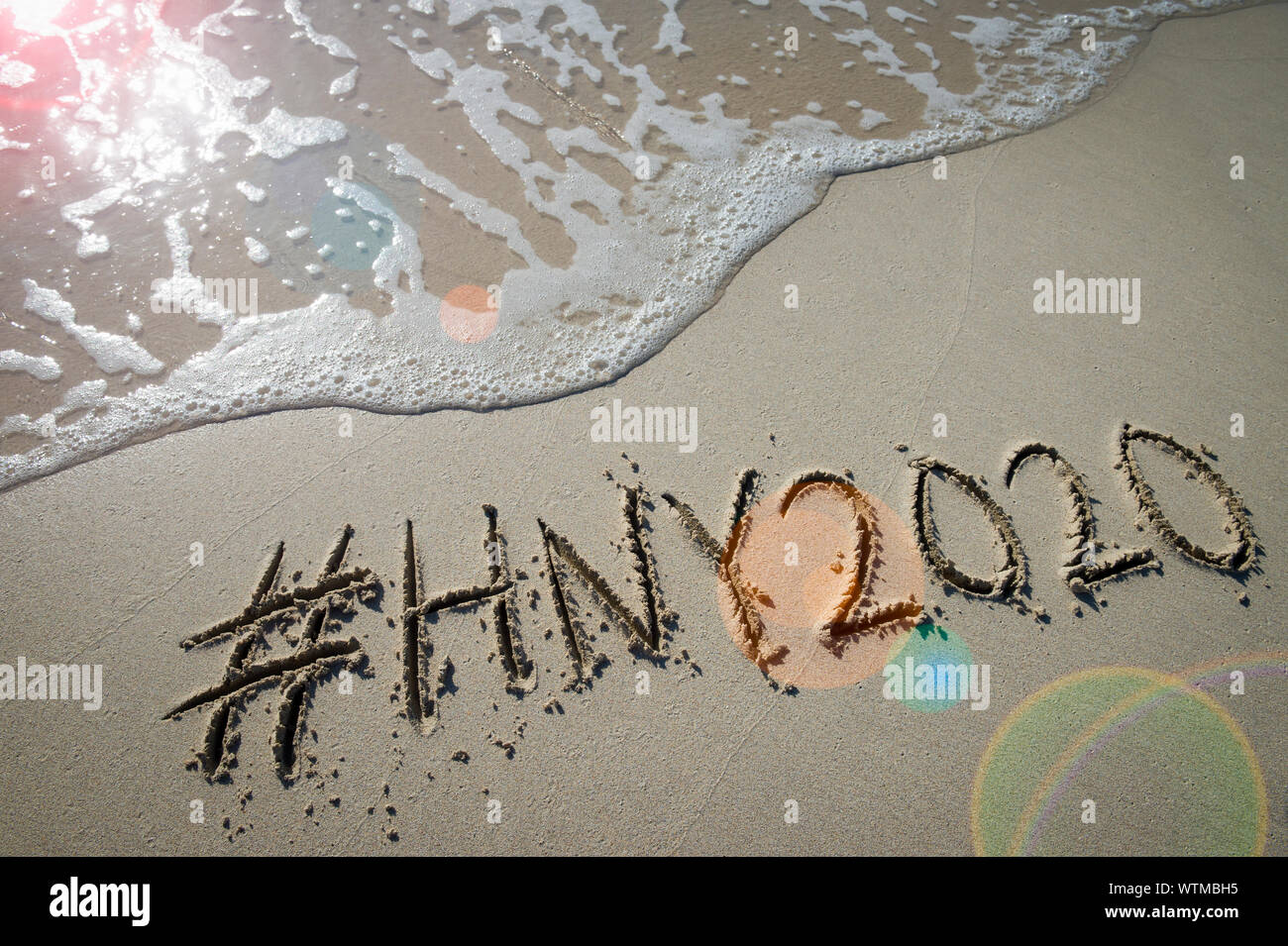 Modern New Year message with social media hashtag for 2020 handwritten in smooth sand with