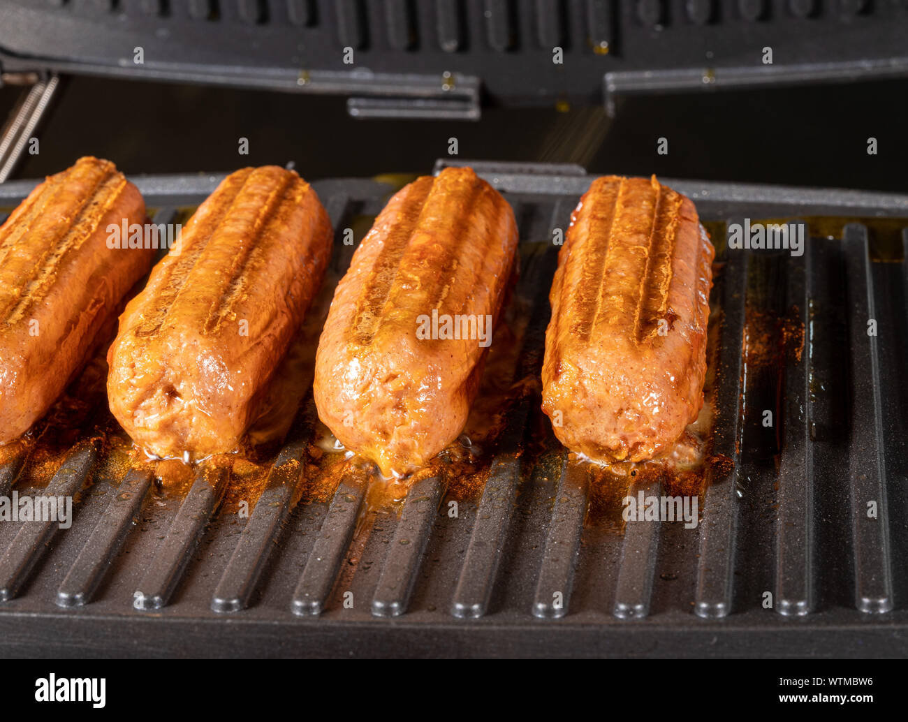 Plant based vegetarian sausages being grilled on griddle Stock Photo