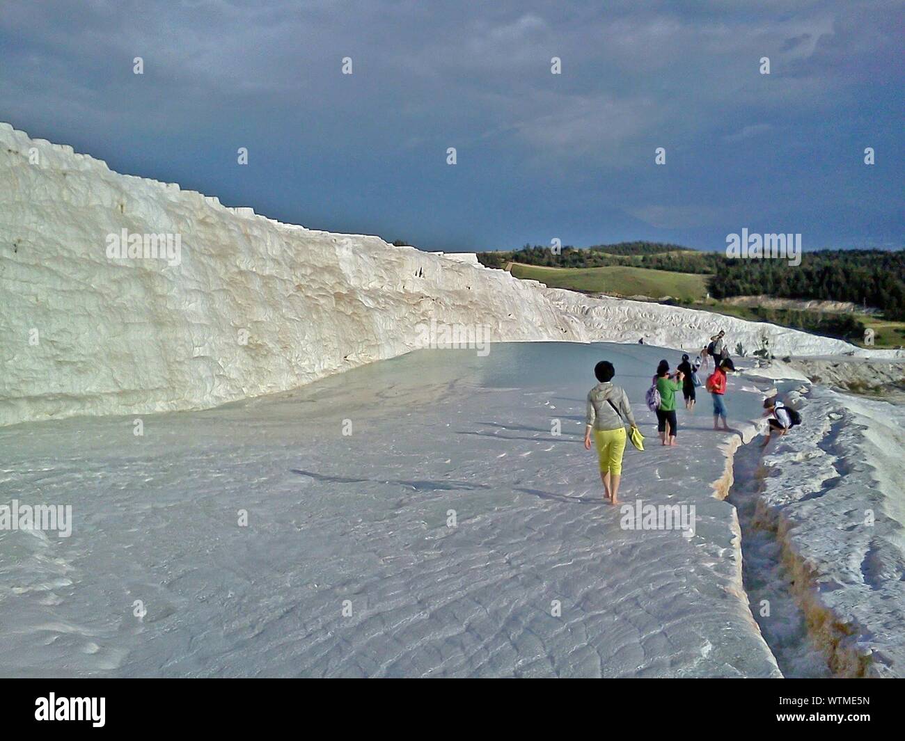 People Walking White Rock Against Cloudy Sky At Pamukkale Stock Photo
