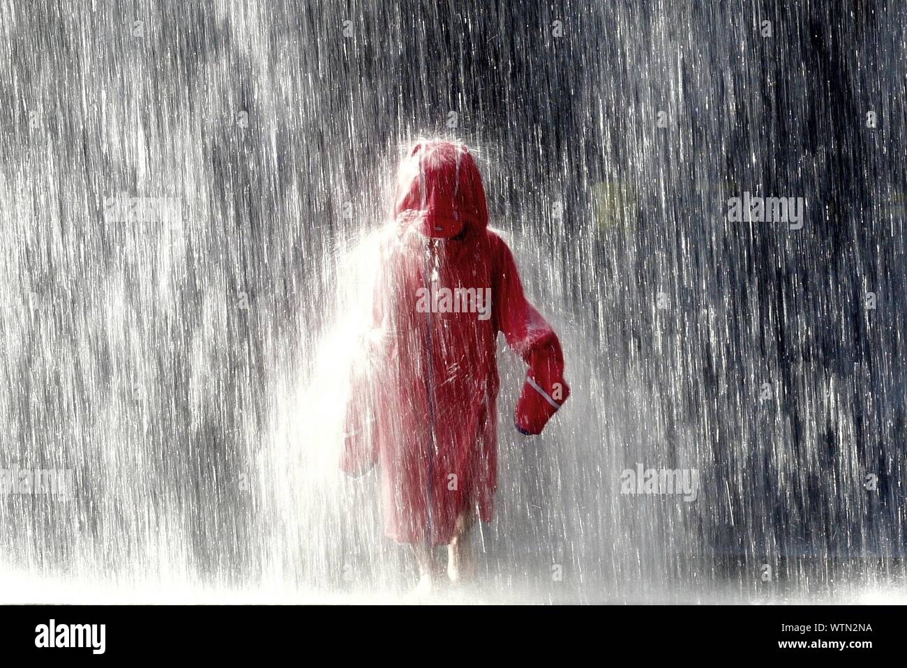 Person In Raincoat Walking In Rain Stock Photo