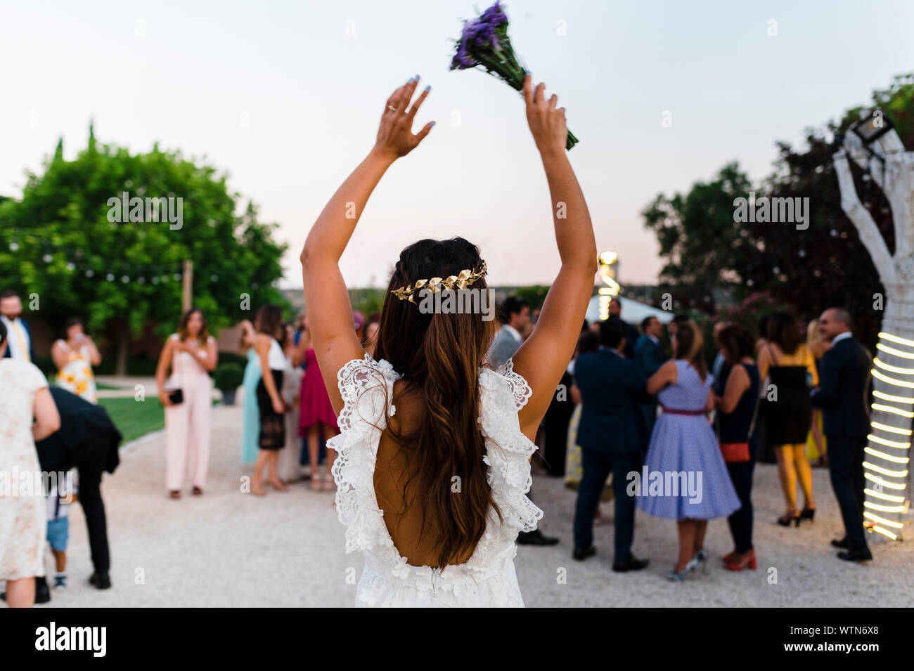 Back view of bride rising arms with bridal bouquet ready to throw Stock Photo