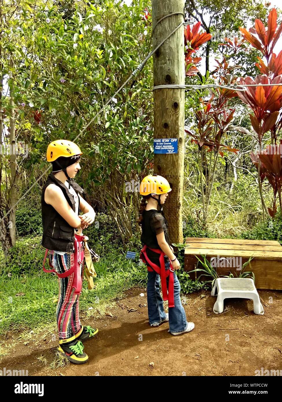 Siblings Wearing Safety Harness And Helmets Standing On Field Stock Photo