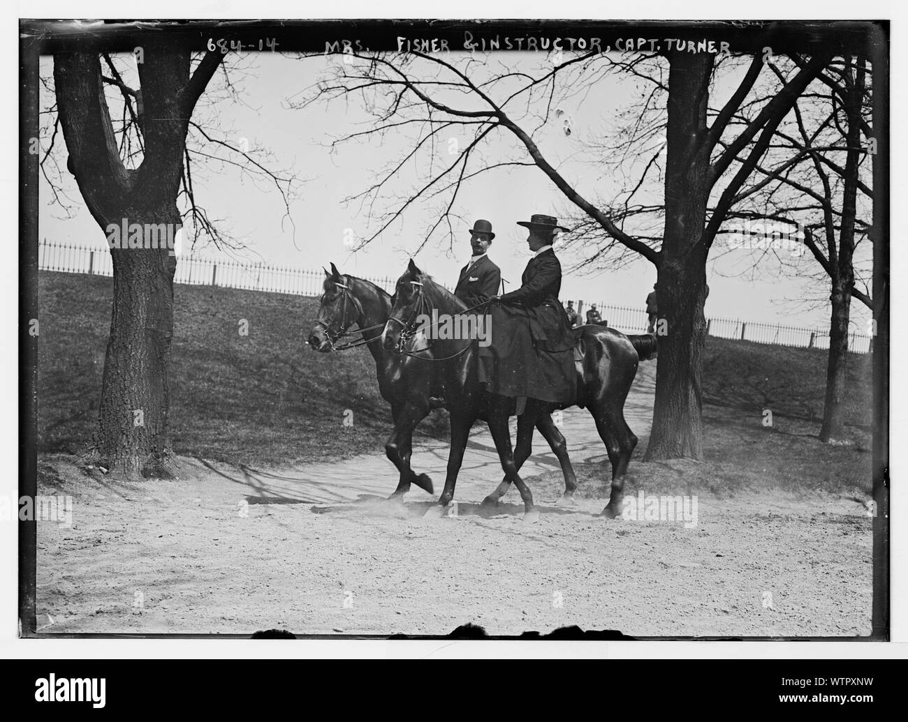 Mrs. Fisher and Capt. Turner, her instructor, horseback riding in park ...
