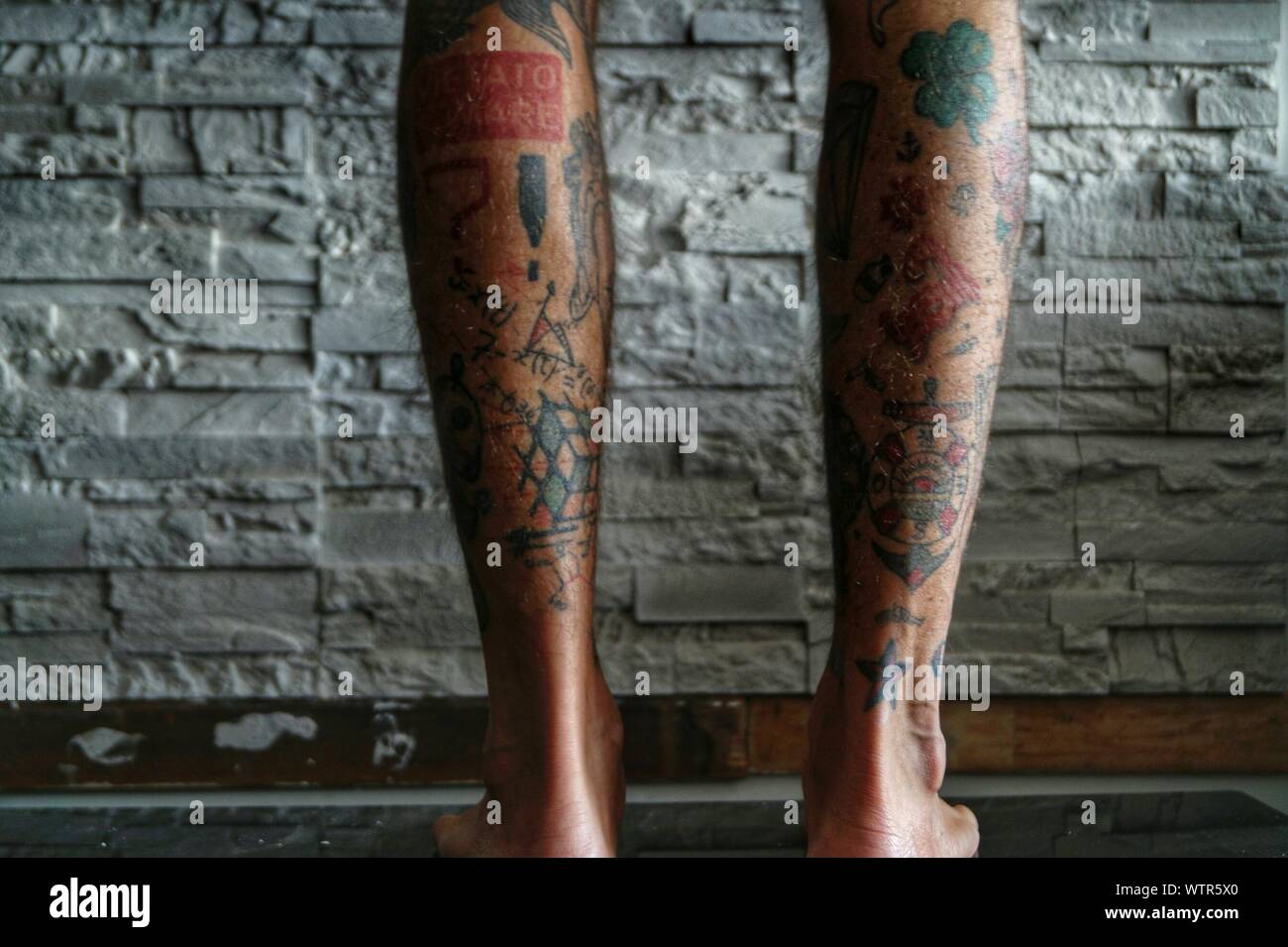 Low Section Of Man With Tattoo Against Brick Wall Stock Photo Alamy
