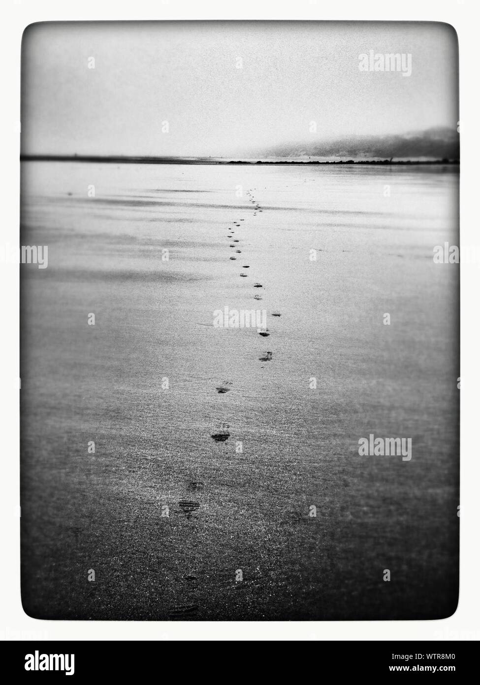 Footprints On Beach Against Sky Stock Photo