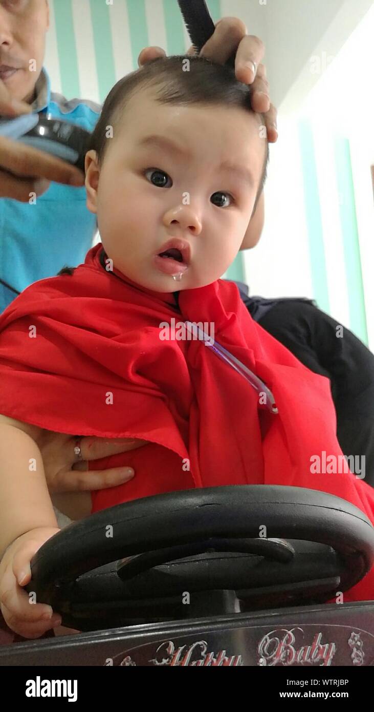 Low Angle View Of Cute Boy Having Haircut Done At Barber Shop
