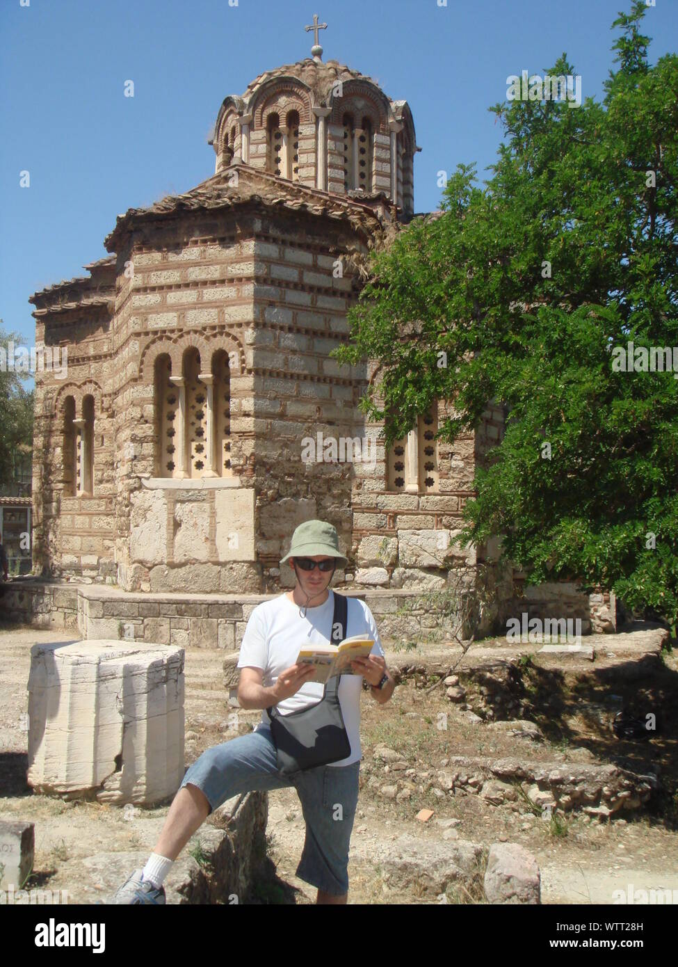 Man Reading Book Against Church Of The Holy Apostles Stock Photo