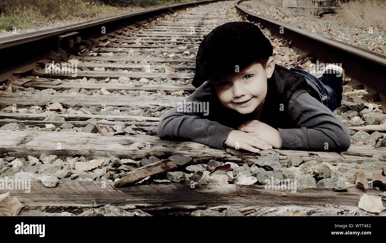 Portrait Of Boy Lying On Railroad Track Stock Photo - Alamy