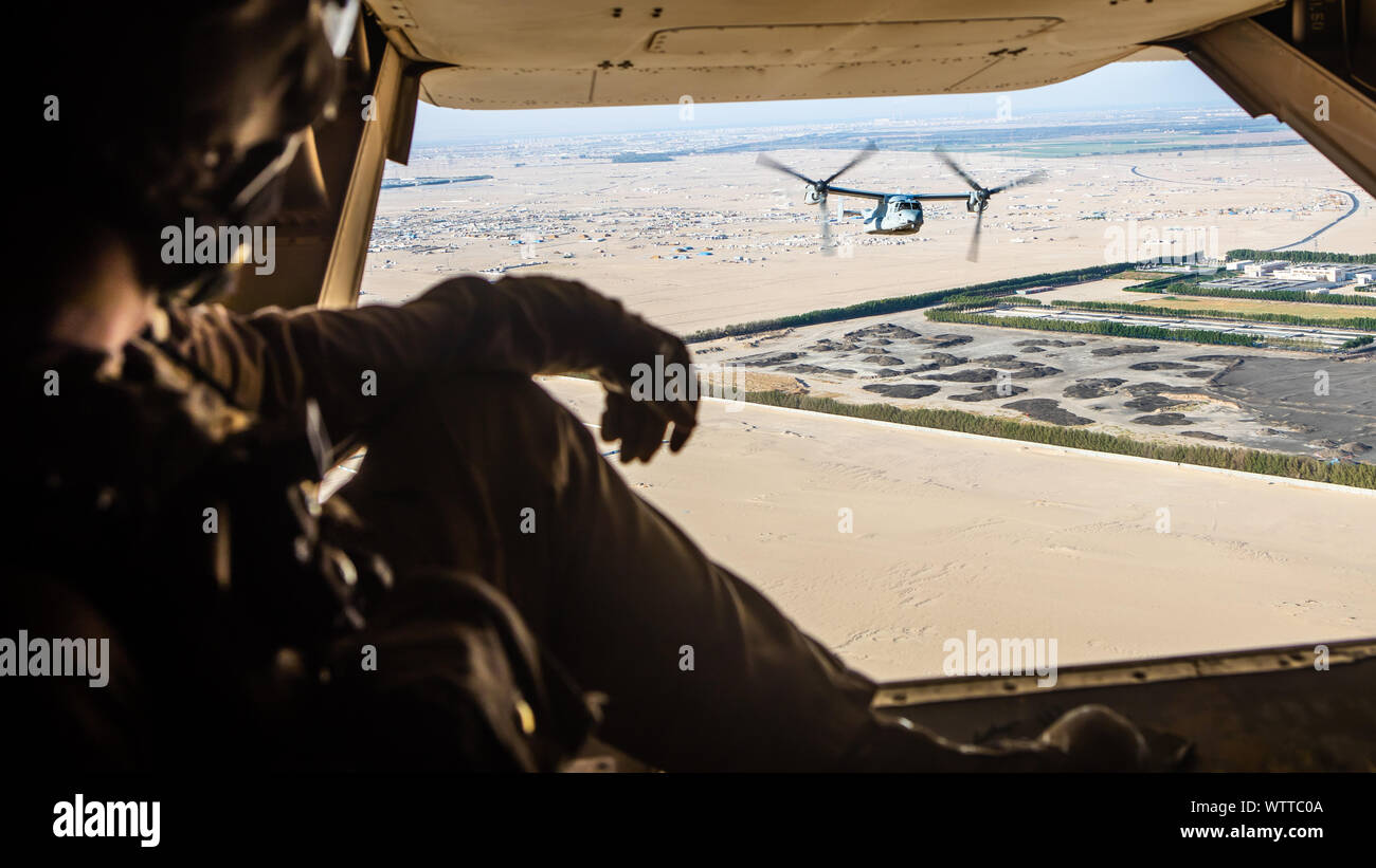 A U.S. Marine Corps crew chief with Marine Medium Tiltrotor Squadron (VMM) 364, attached to Special Purpose Marine Air-Ground Task Force-Crisis Response-Central Command, watches an MV-22 Osprey fly during a tactical recovery of aircraft and personnel exercise Sept. 08, 2019. A Marine Air Ground Task Force is specifically designed to be capable of deploying aviation, ground, and logistics forces forward at a moment’s notice. (U.S. Marine Corps photo by Sgt. Branden Bourque) Stock Photo