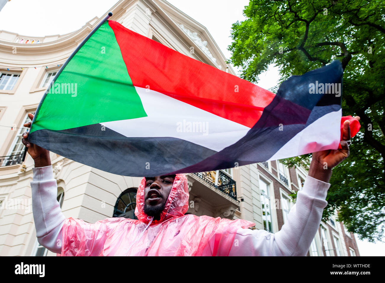 A Sudanese protester holds a Sudanese flag during the demonstration.From September 6th to 11th, an international Sudanese march took place starting in London and ending in The Hague after stopping in France and Belgium. On September 11th, the march arrived in front of the International Criminal Court building, situated in The Hague. The march was held in solidarity with the Sudanese revolution and calls for the prosecution of military criminals in Sudan. The march was organized by the Sudanese Initiative Europe. Stock Photo