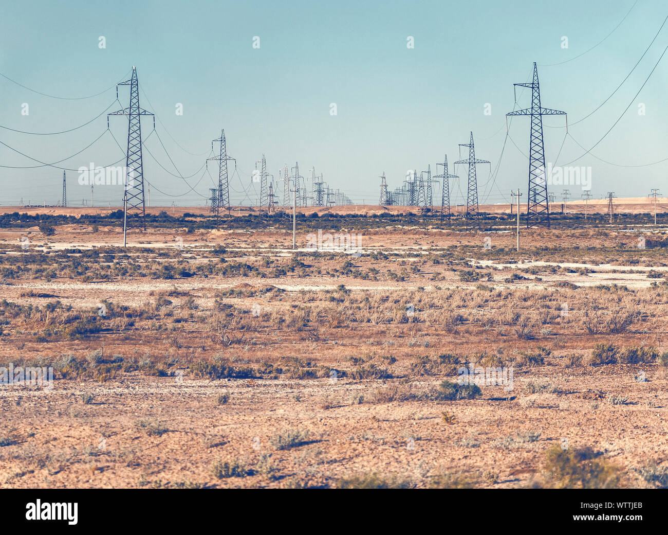 Rows of high voltage power line pylons in desert Stock Photo