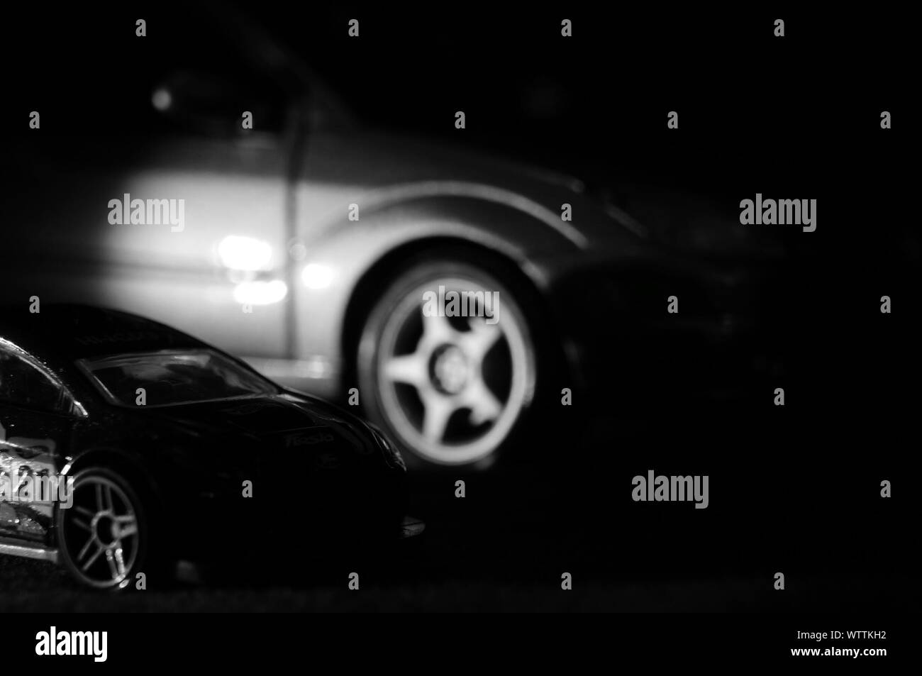 Close-up Of Toy Car Against Motor Vehicle At Night Stock Photo