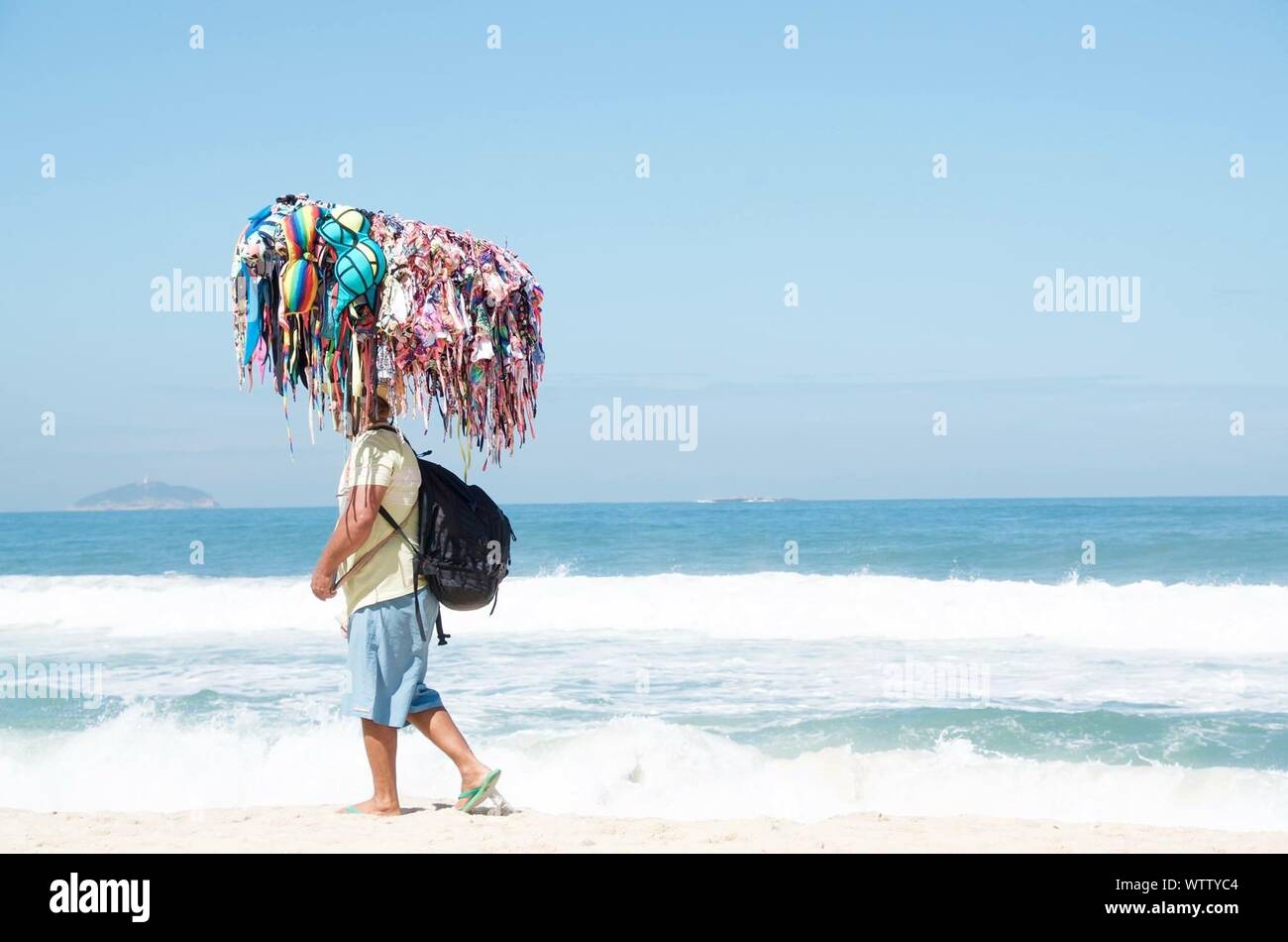 Side View Of Man Selling Bikinis On Shore At Beach Stock Photo