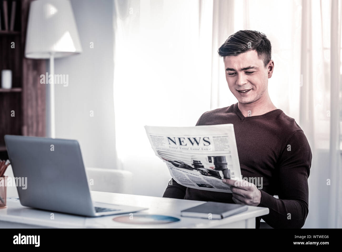 Smiling man with stylish haircut being amused by information Stock Photo