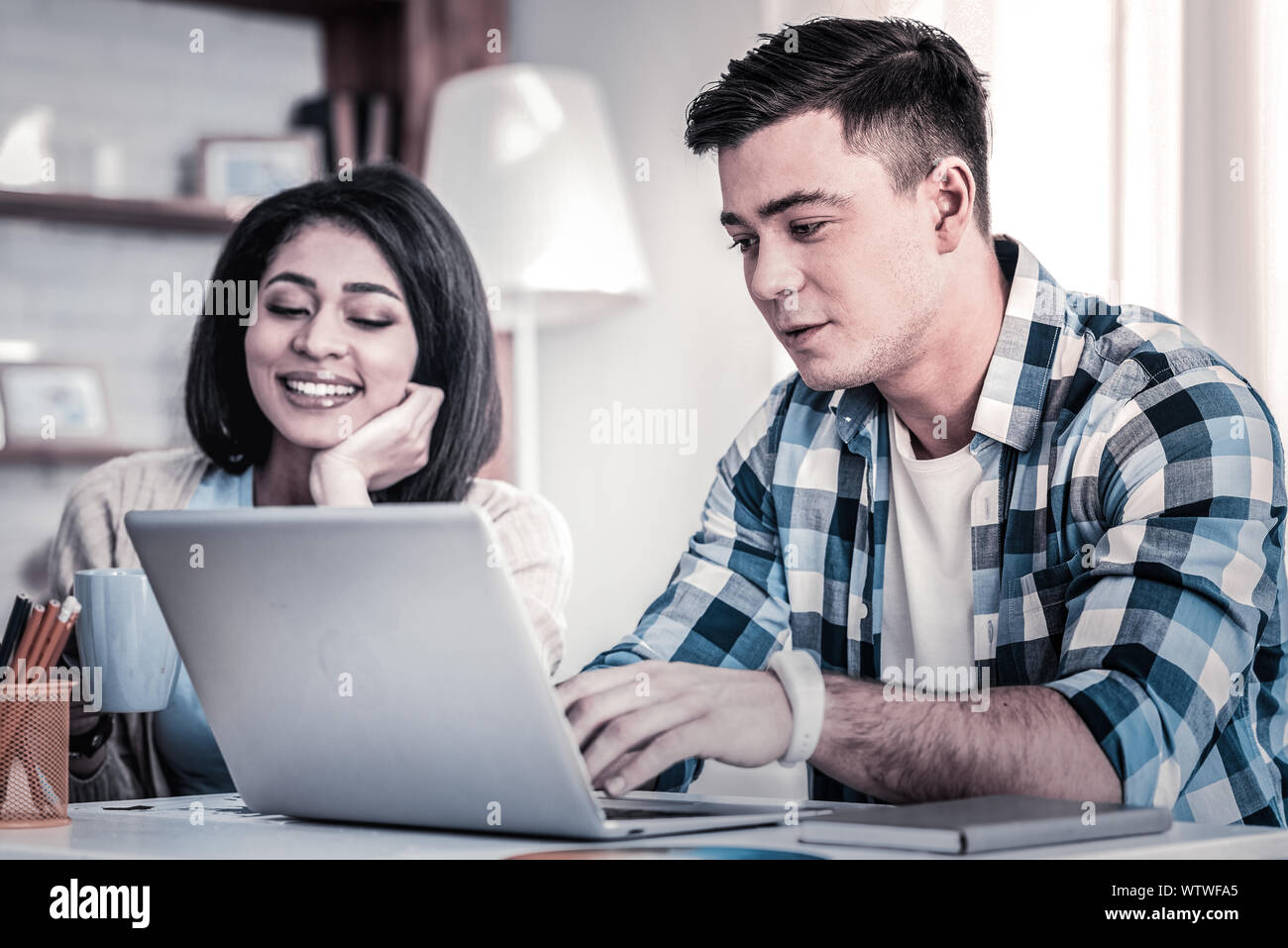 Hairy man in blue shirt busy with his computer Stock Photo