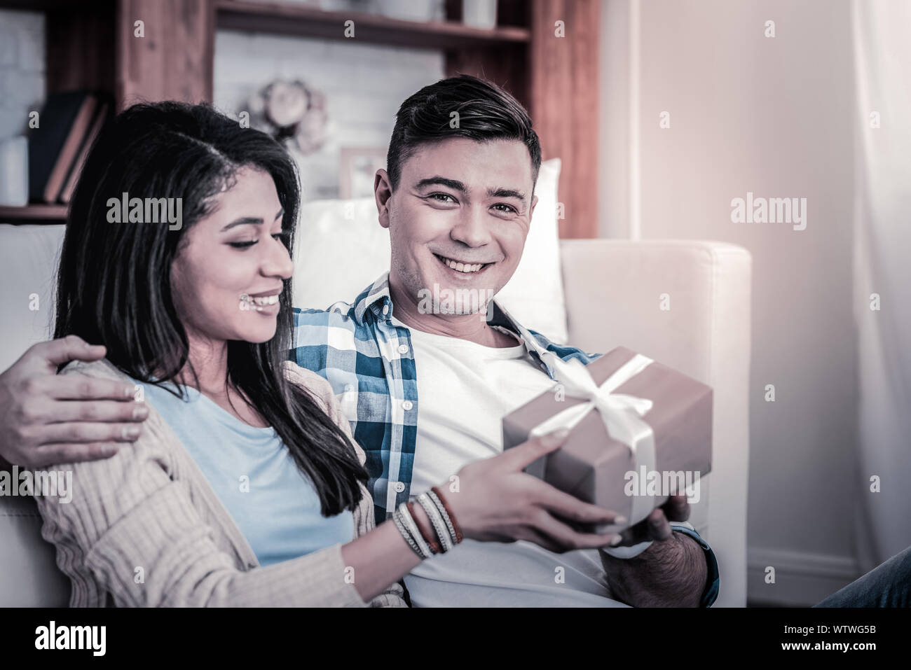 Smiling man delightedly giving decorated box to his girl Stock Photo