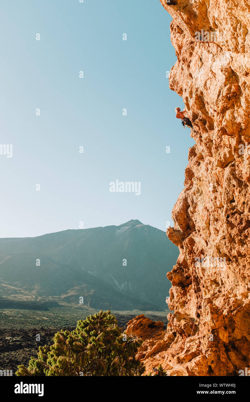 Pulled back view of male climber on wall with El Teide in the back Stock Photo