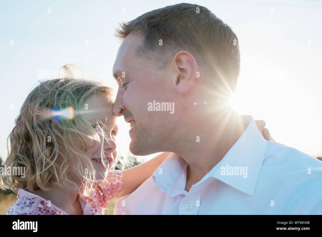 portrait of father carrying his daughter outside at sunset Stock Photo