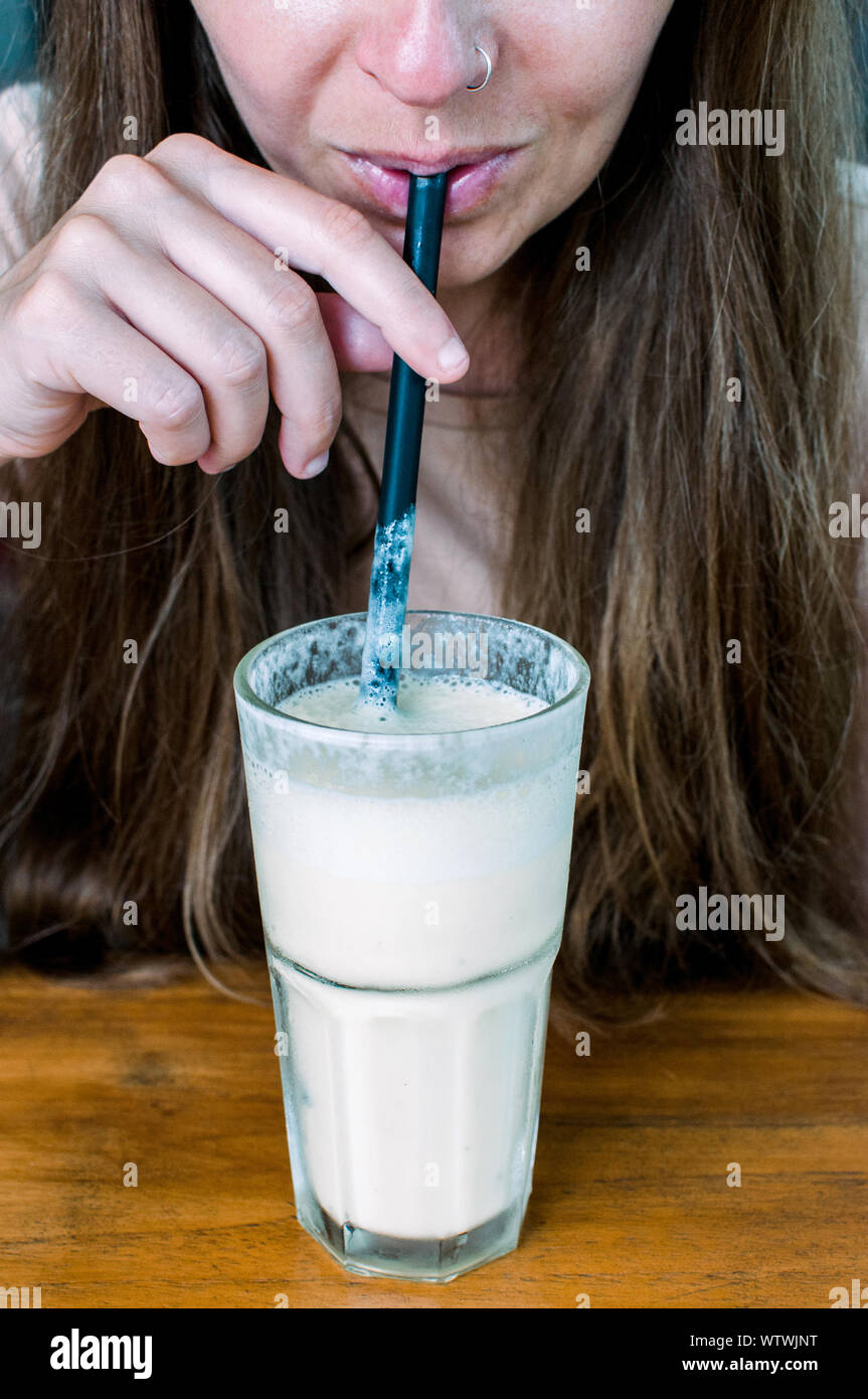 Young anonymous woman drinks smoothie with straw Stock Photo
