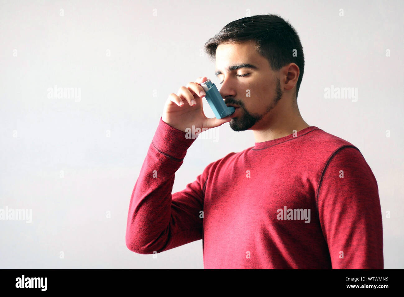 Someone Using Blue Inhaler Health and medicine - Young man using blue asthma inhaler to prevent an ...