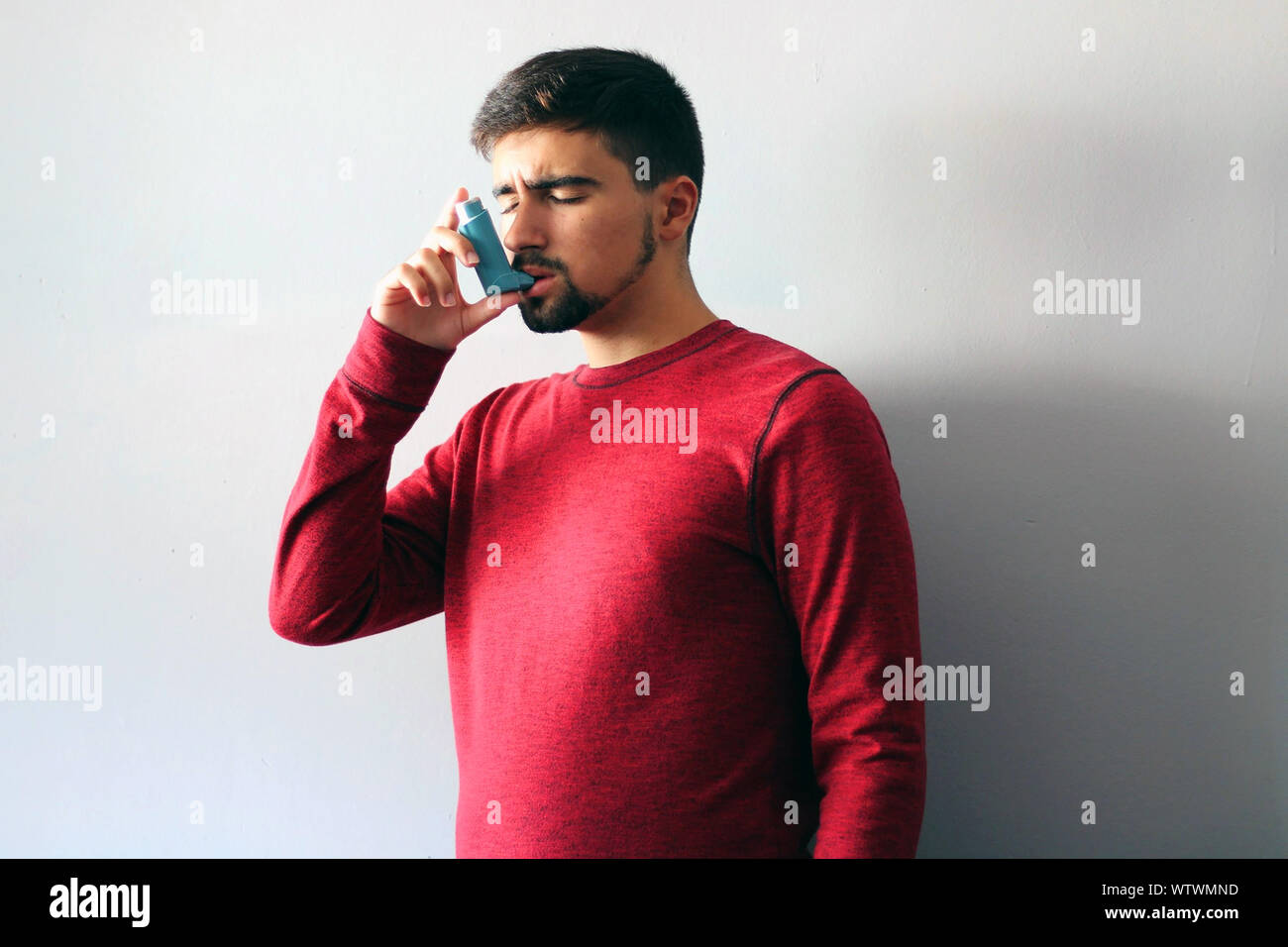 Someone Using Blue Inhaler Health and medicine - Young man using blue asthma inhaler to prevent an ...