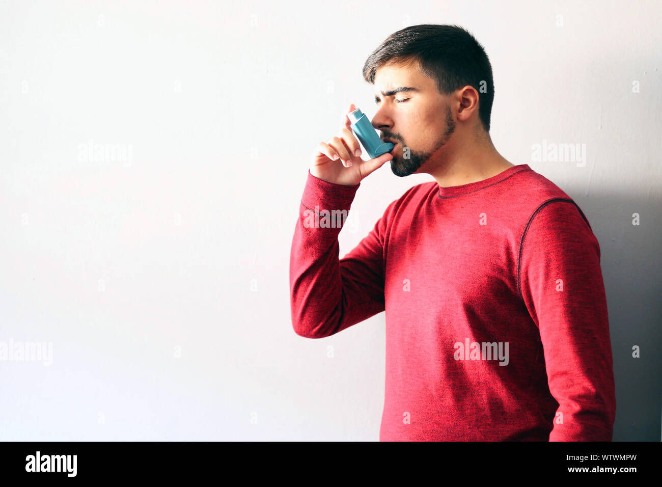 Someone Using Blue Inhaler Health and medicine - Young man using blue asthma inhaler to prevent an ...