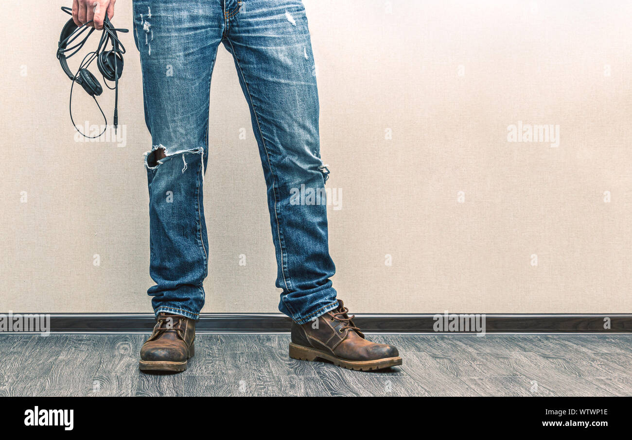 Young fashion Man in jeans and boots with headphones on wooden floor Stock Photo